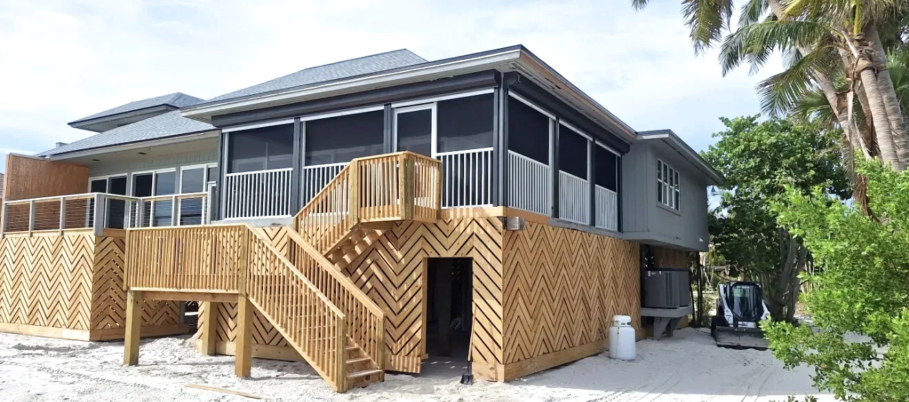 Elevated Fort Myers beach house with a screened porch, horizontal metal railing panels, chevron wood lattice skirting and stairs