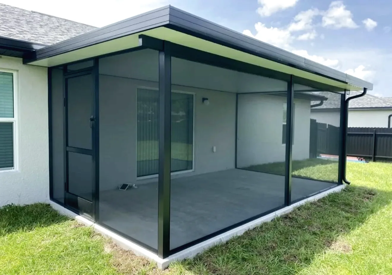 Dark bronze screen room with solid aluminum roof, gutter and screen door on the rear of a white stucco house