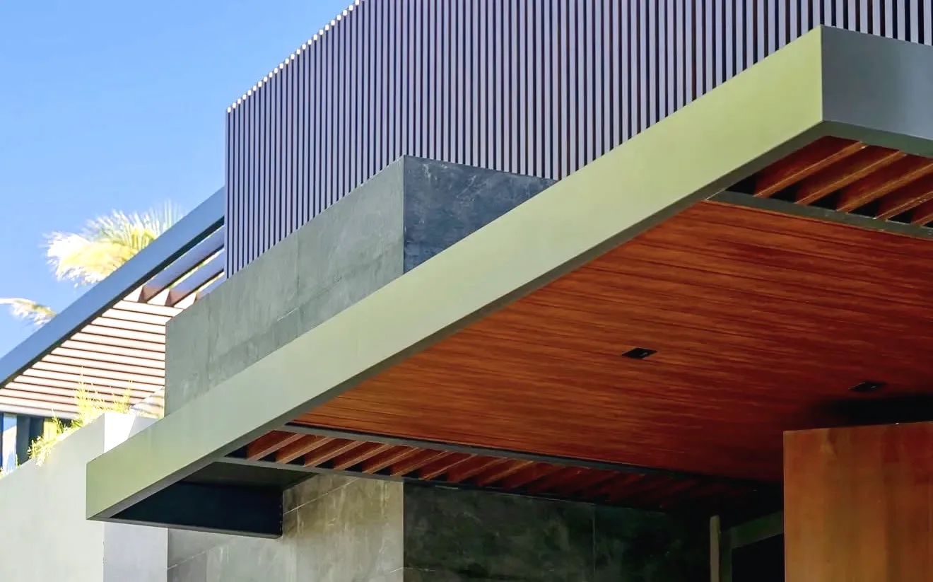 Cantilevered canopy with a wood-plank ceiling and exposed rafter tails, vertical slat screen above, and concrete walls
